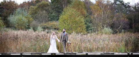 A bride and groom on the boardwalk in front of autumnal trees