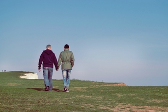 A couple walking hand in hand on a costal cliff-top