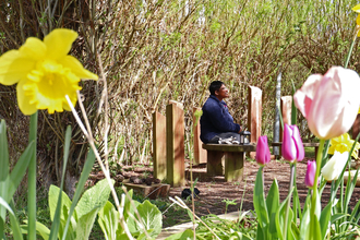 A person sitting on a bench in the sunshine