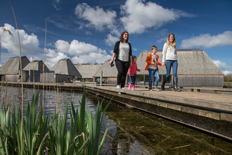 Two women walking with 2 children on the boardwalk, away from the floating Visitor Village at Brockholes Nature Reserve