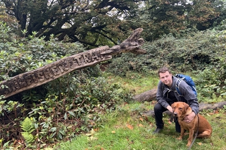 Rory and his dog Cooper crouched down next to the Kingfisher Trail sign