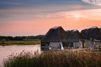 A couple standing on the boardwalk in front of Brockholes Visitor Village at sunset