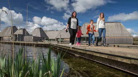 Two women walking with 2 children on the boardwalk, away from the floating Visitor Village at Brockholes Nature Reserve