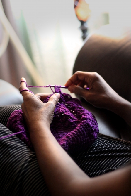 Woman sitting and knitting with purple thread