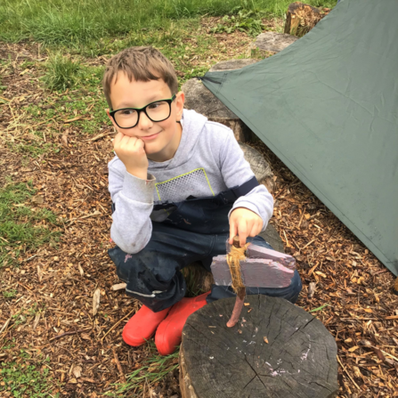 A child smiling with his wooden play axe