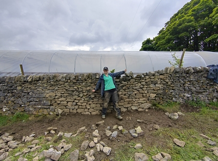 A woman standing in front of a dry stone wall