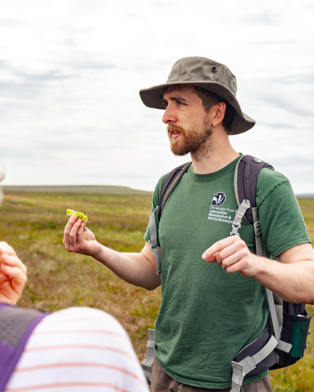 Nathan Thomas, holding some sphagnum moss, leading a guided walk on Darwen Moor.