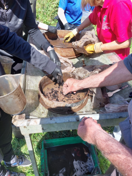 Volunteers and young people find pieces of burned hazelnut and flint when sieving bags of soil at Lunt Meadows