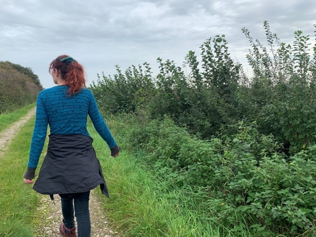 Amy walking on a path next to some shrub