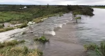 A large volume of water from the River Alt pours over the spillway into Lunt Meadows