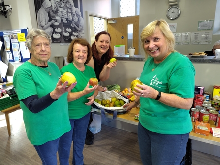 A group of volunteers holding donated apples