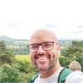 A man stood in front of a green landscape