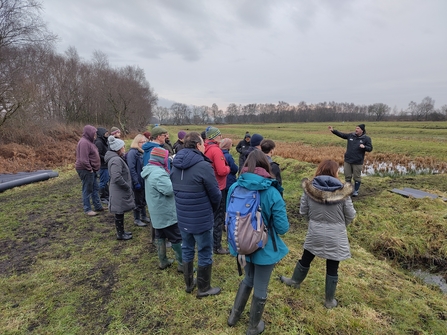 A group of people listening to a talk in a green field