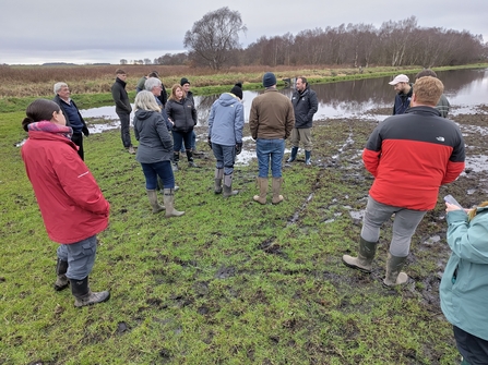 A group of people stood in a partially flooded field