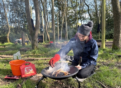 Forest School trainee lighting a fire